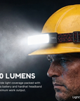 Person wearing a yellow hard hat with a headlamp labeled '500 LUMENS' on a dark background.